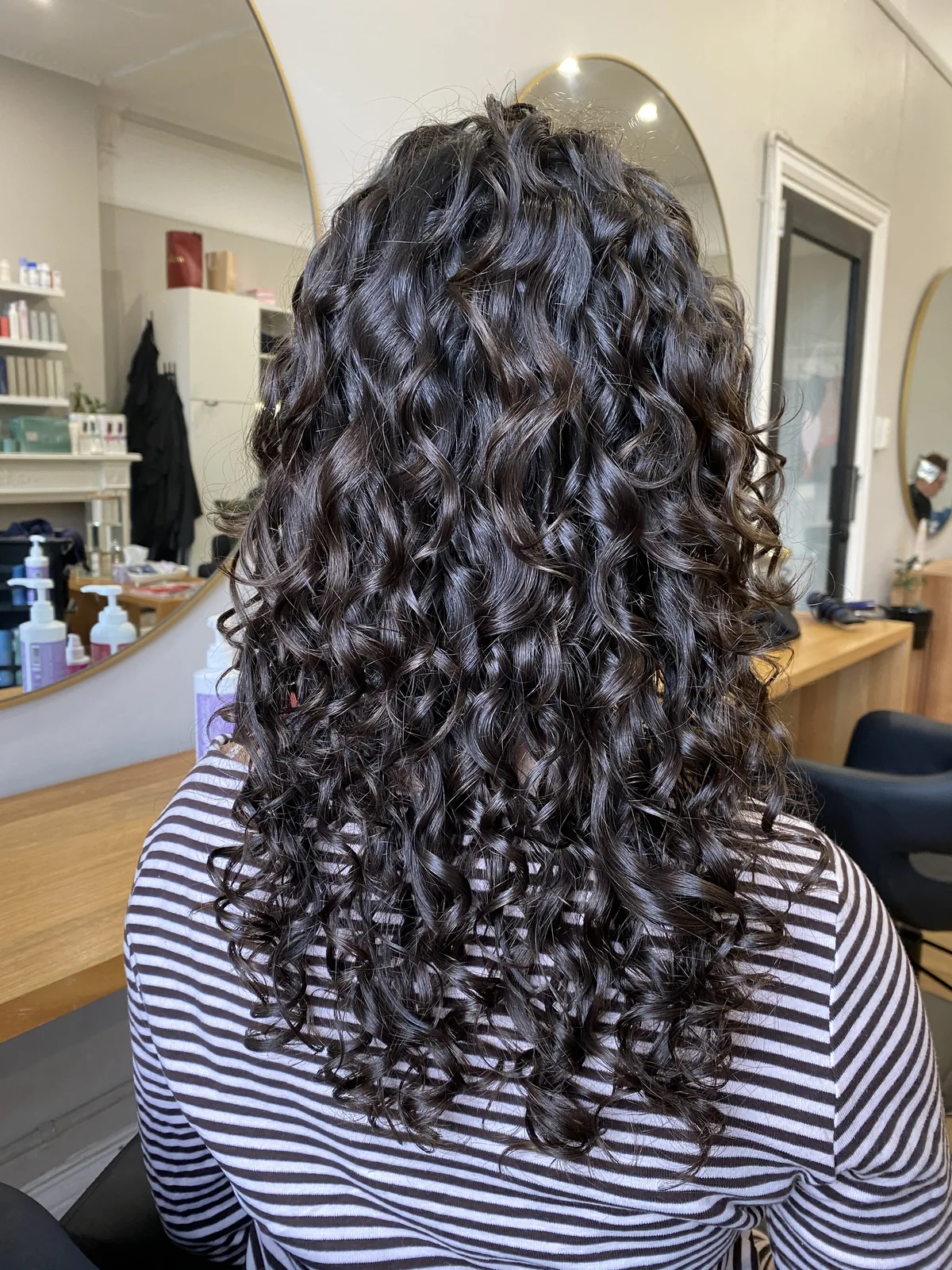 Glossy dark curls shaped and styled by Cas